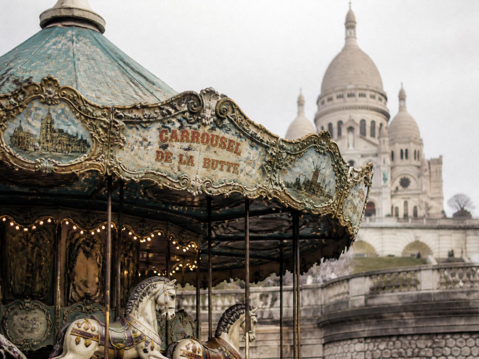 A weathered teal and gold carousel canopy in Montmartre with Sacré-Cœur behind